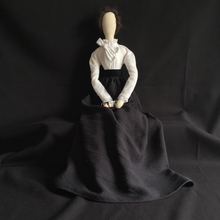 Load image into Gallery viewer, A full seated image of Belle, a wee box of red tipped matches in her hand.