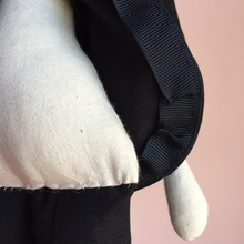 Load image into Gallery viewer, The inside curved edge of Madeleine's jacket. We see the trim work to finish the seams, as well as the tiny row of stitches where her leg has been hand sewn to her body.