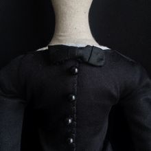 Load image into Gallery viewer, A close up of Madeleine's body from her neck to mid torso, set against a dark back drop. The focus is on the row of buttons on her jacket, the antique silk bow at her neckline, and a peek of the antique linen at her collar.